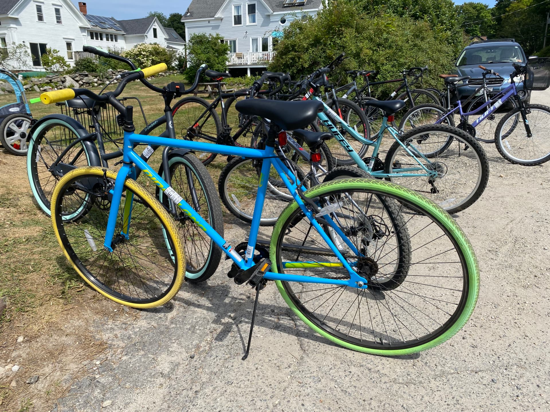 Enie's rental bikes lined up on Peaks Island, including a blue adult bike with yellow and green tires