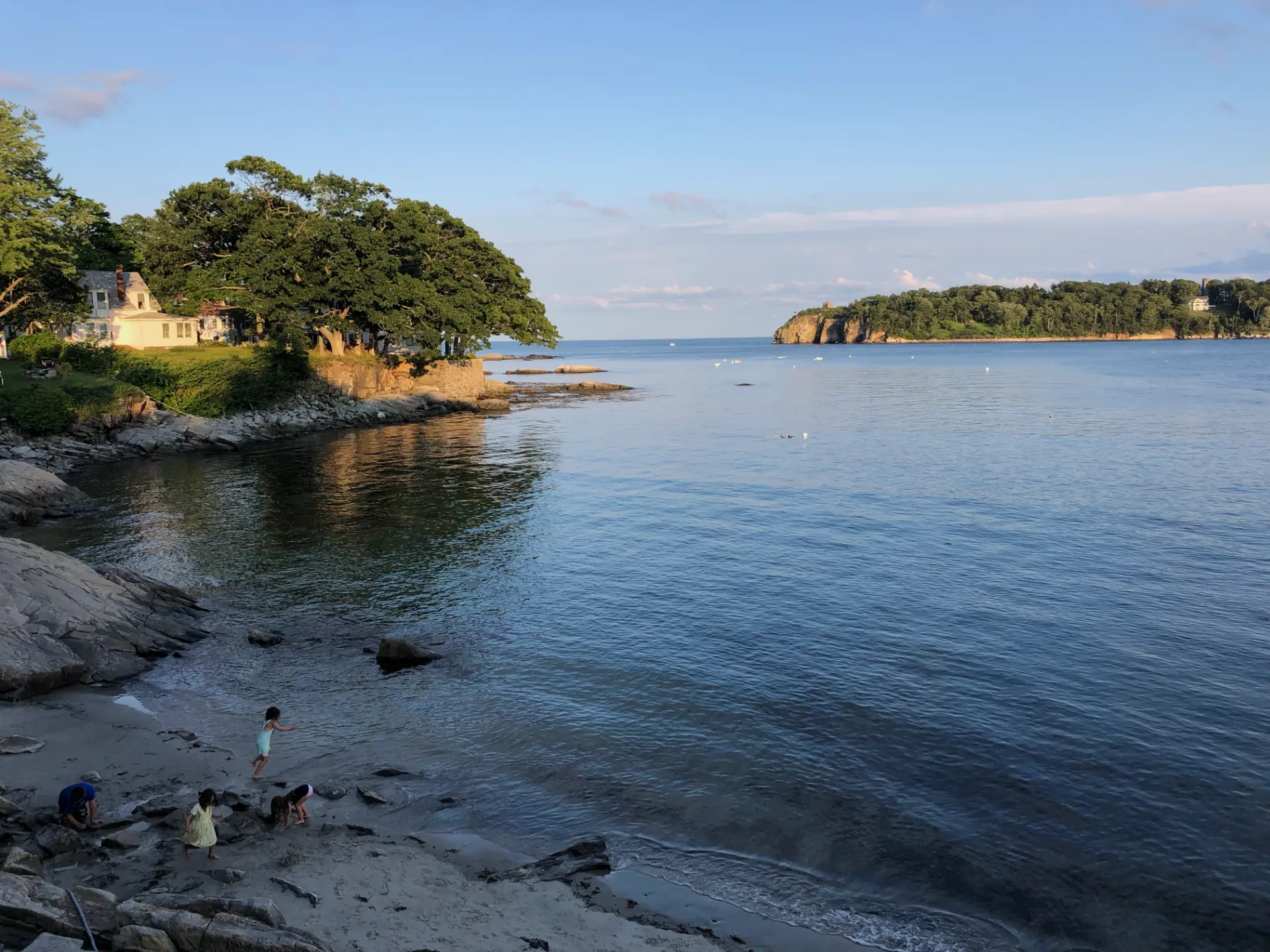 Kids playing along the rocky shore of Sandy Beach on Peaks Island at golden hour