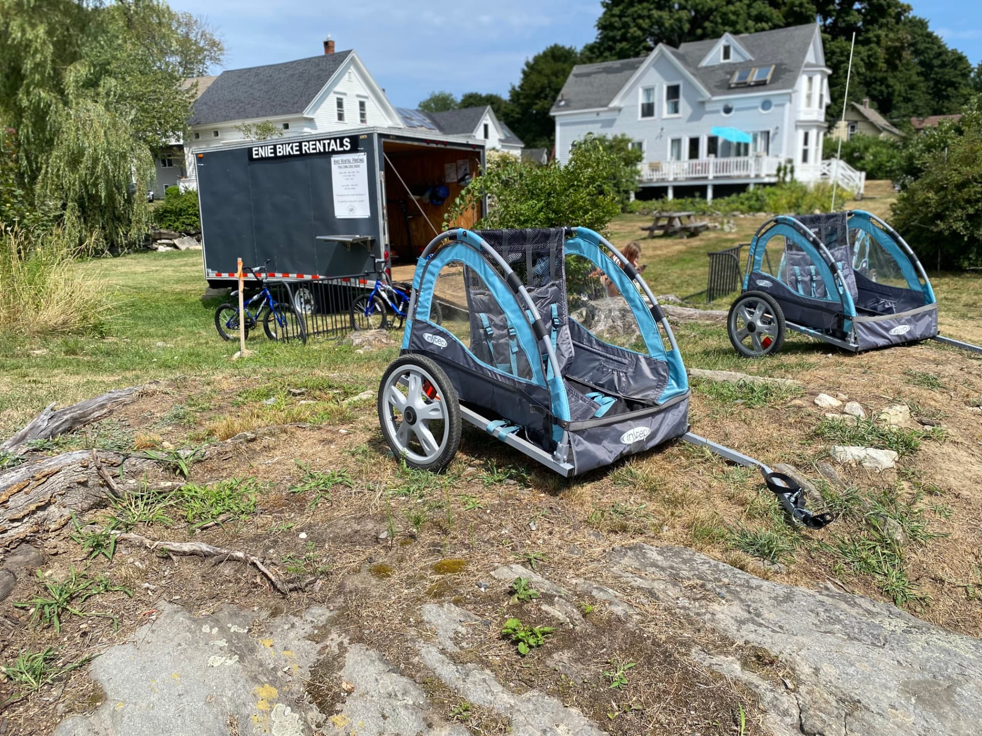 Two InStep kid trailers parked on the grass outside the Enie Bike Rentals trailer on Peaks Island